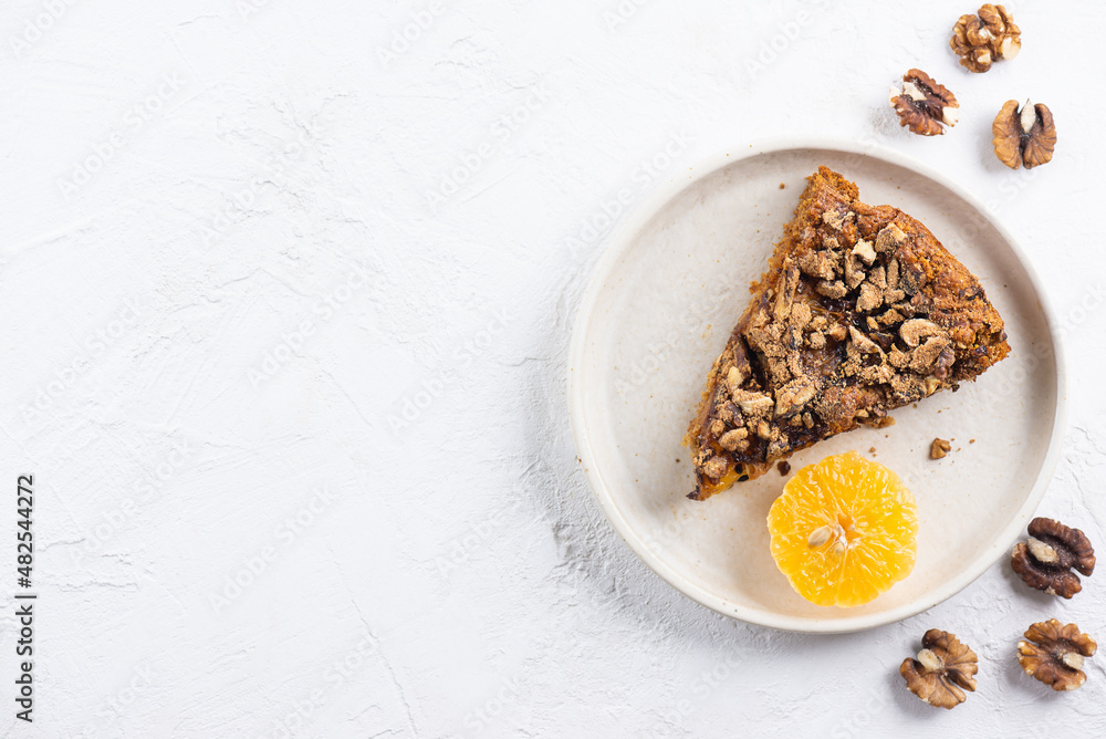 A piece of homemade mandarin pie with walnuts in a plate. Sugar, gluten and lactose free, vegan. Horizontal orientation, copy space, top view. A piece of homemade mandarin pie with walnuts in a plate. Sugar, gluten and lactose free, vegan. Horizontal orientation, copy space, top view.