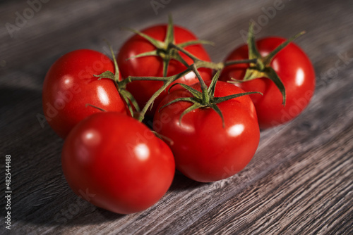 red tomatoes on a branch on a wooden grey table