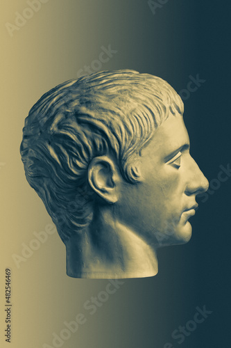 Bronze color gypsum copy of ancient statue of Germanicus Julius Caesar head for artists on brass background. Renaissance epoch. Plaster sculpture of man face. Template for art design