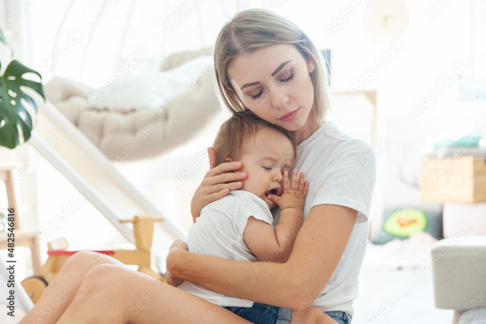 Caring mom lulls her little daughter in her arms in the playroom Caring mom lulls her little daughter in her arms in the playroom