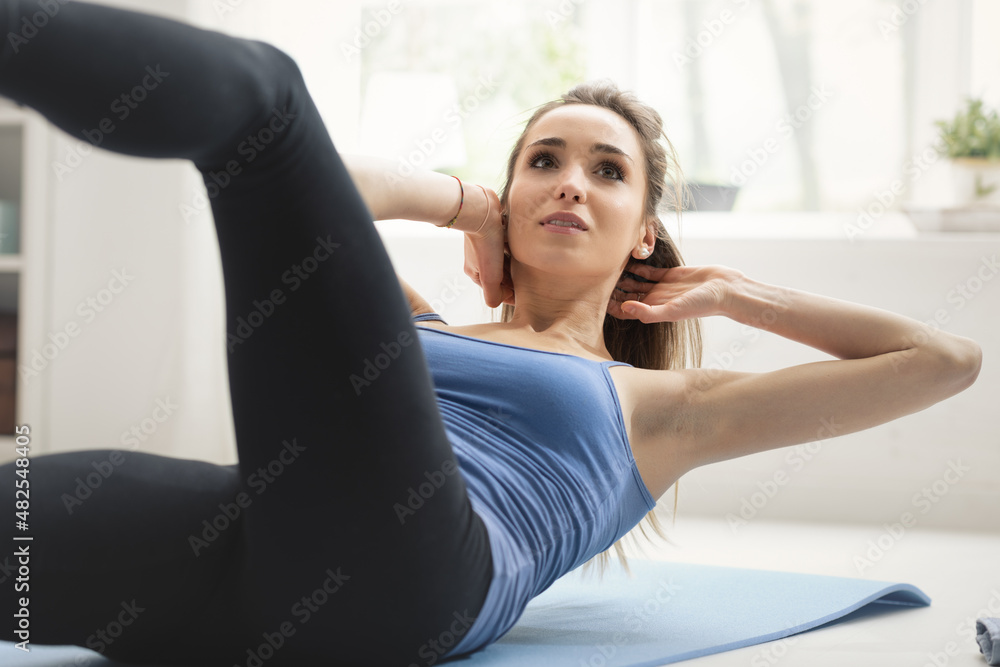 Fit woman doing sit ups at home on the floor