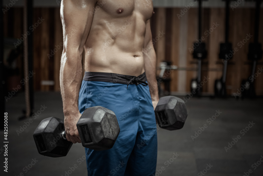 Muscular man holding heavy dumbbells in the gym Muscular man holding heavy dumbbells in the gym