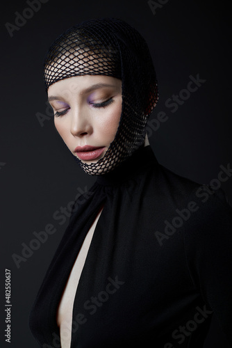 Woman with nylon stocking mesh on head. Black mesh bandage on face woman in black dress with a low neckline