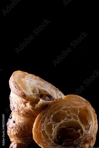 Homemade croissant cut in half on a black background