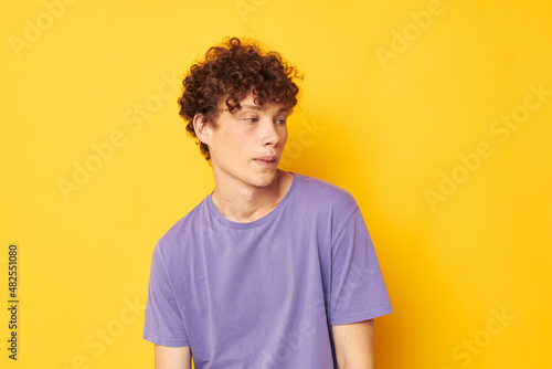 guy with curly hair in purple t-shirts studio yellow background