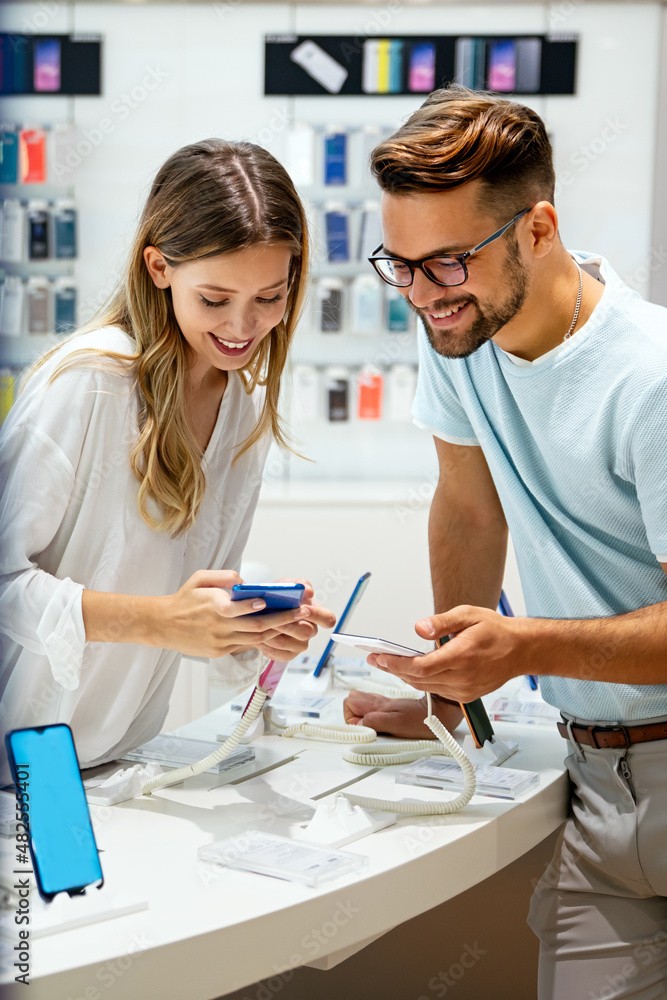 Fototapeta premium Happy young people buying new smartphone in mobile shop. Technology device shopping concept