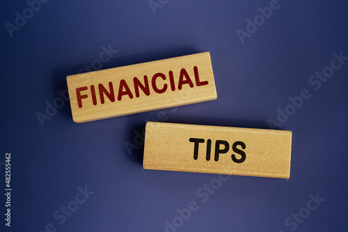 Wooden blocks form the words 'Financial tips' on a dark blue background. Business concept