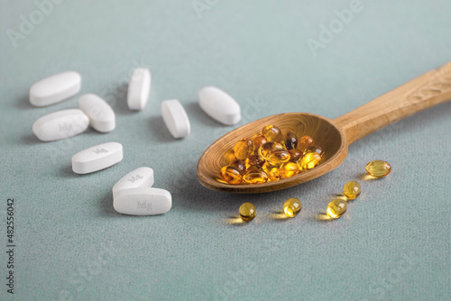 A complex of Mg ( magnesia, magnesium ) and vitamin D ( omega 3 ) capsules for treatment and human health on a light background. Copy space.