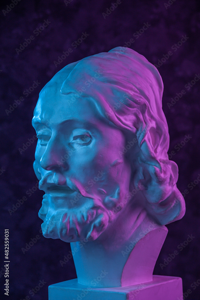 Colorful gypsum copy of ancient statue of John the Baptist head for artists on a dark textured background. Plaster sculpture man face. John baptized Jesus. Art poster in purple and blue bright colors. Colorful gypsum copy of ancient statue of John the Baptist head for artists on a dark textured background. Plaster sculpture man face. John baptized Jesus. Art poster in purple and blue bright colors.