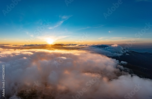 Sun shining brightly above white fluffy clouds at sunrise © YouraPechkin