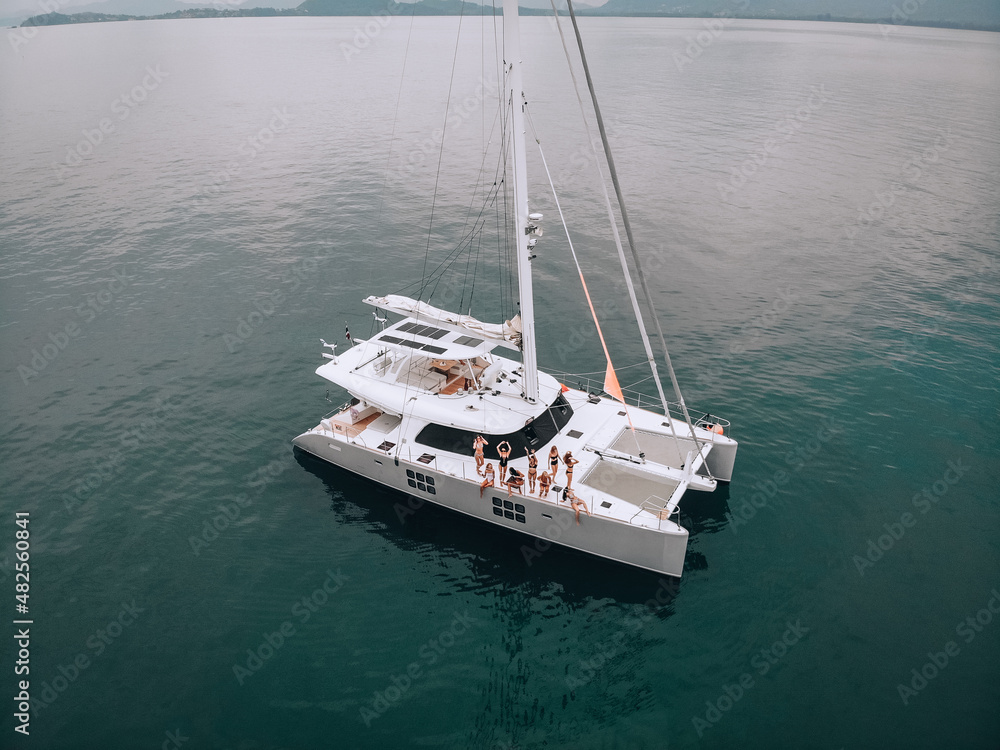 Naklejka premium Picture of wonderful dancing girls in swimsuits on a luxury white yacht on the turquoise sea. Photo from a bird's-eye view. Enjoy vacation. Party at the sea. The concept of relaxation.