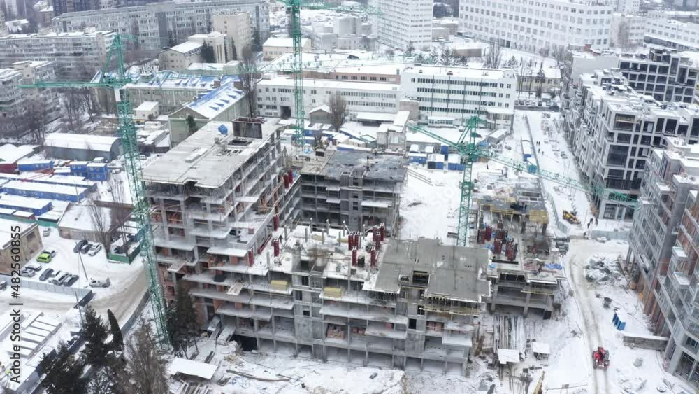 Aerial view of construction site in winter city. Building construction, construction industry. Construction workers on a building site with crane. Aerial view of construction site in winter city. Building construction, construction industry. Construction workers on a building site with crane.