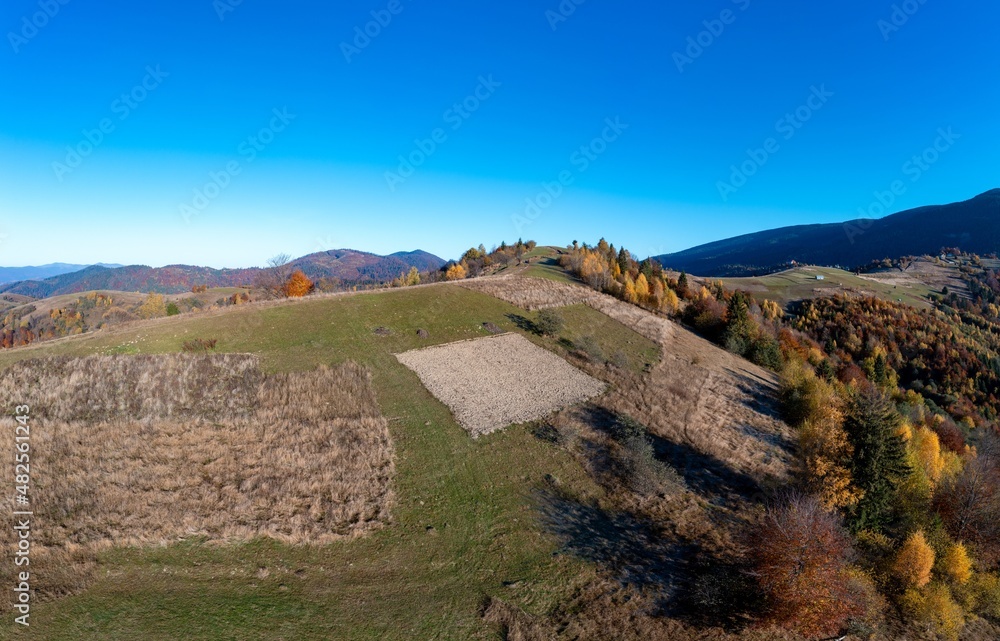Harvested fields on slope of mountain under cloudless sky