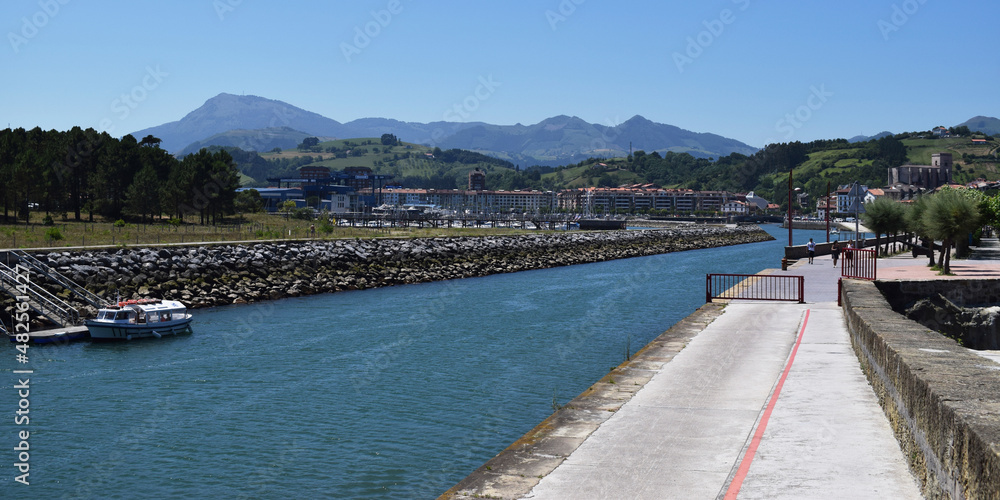 Paisaje marítimo con puerto y acantilados. 