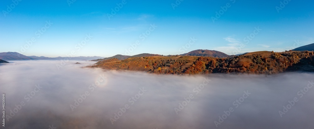 Fog among peaks of high autumn mountains with forests