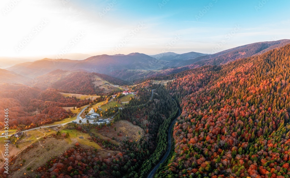 High mountain with red and green forests under bright sunset