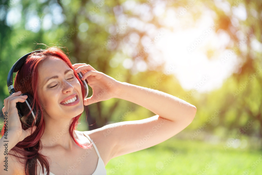 Young woman happens to have music in a summer park Young woman happens to have music in a summer park