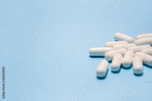 White tablets or capsules lie on a light blue background with space for text. Pharmaceutical, Covid-19 or coronavirus, selective focus