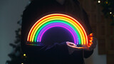 Girl holds neon led rainbow in hands in the night