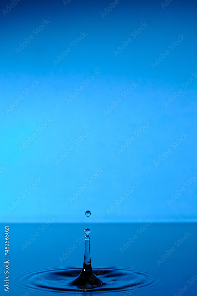 Water splashes after raindrop falls.Blue abstract background with splash of drop of water.