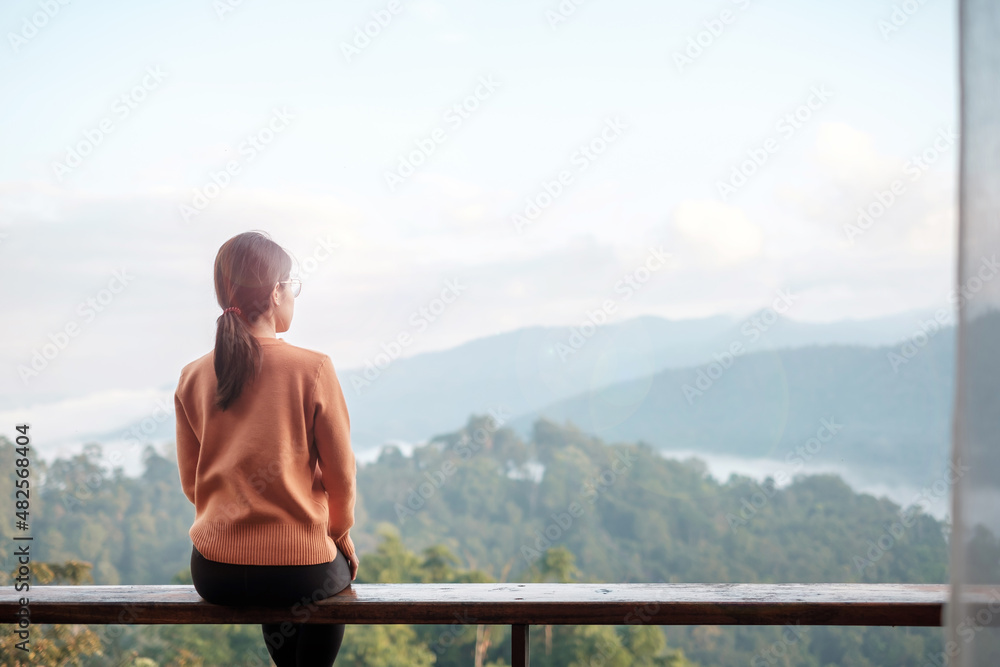 Happy woman relaxing and looking mountain view at countryside home or homestay in the morning. Vacation, blogger, SoloTravel, journey, trip and relaxing concept