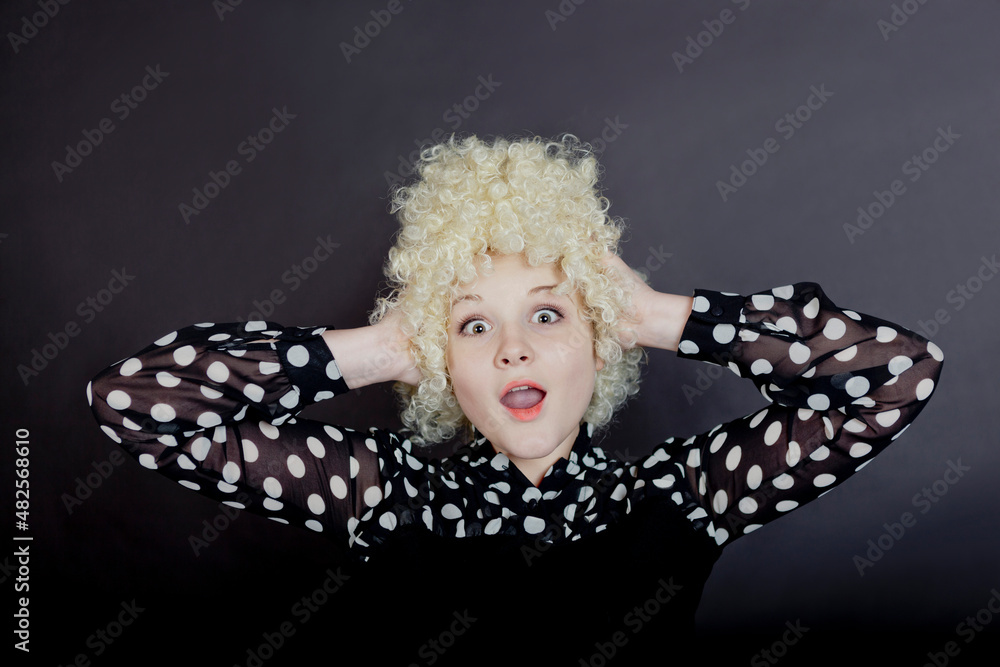 Curly girl - blonde in a blouse with polka dots like a clown screams on a black background Curly girl - blonde in a blouse with polka dots like a clown screams on a black background