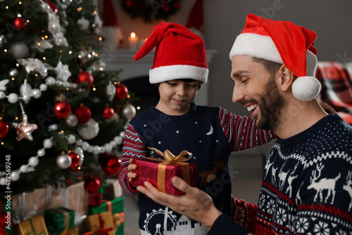 Cute son giving present to his father at home. Christmas celebration