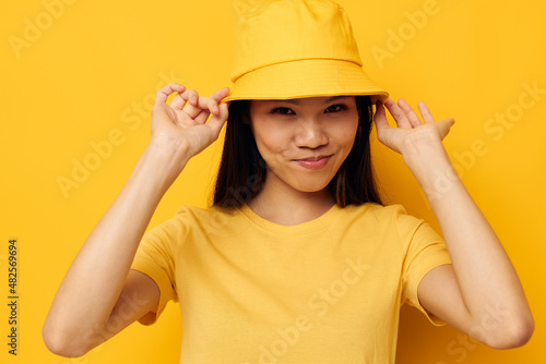 pretty brunette in a yellow t-shirt and hat posing emotions yellow background unaltered © Tatiana