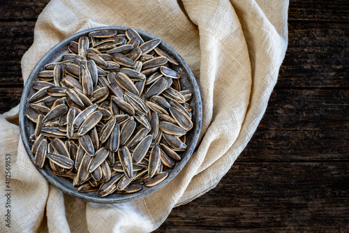Many sunflower seeds on the old rustic wooden bowl