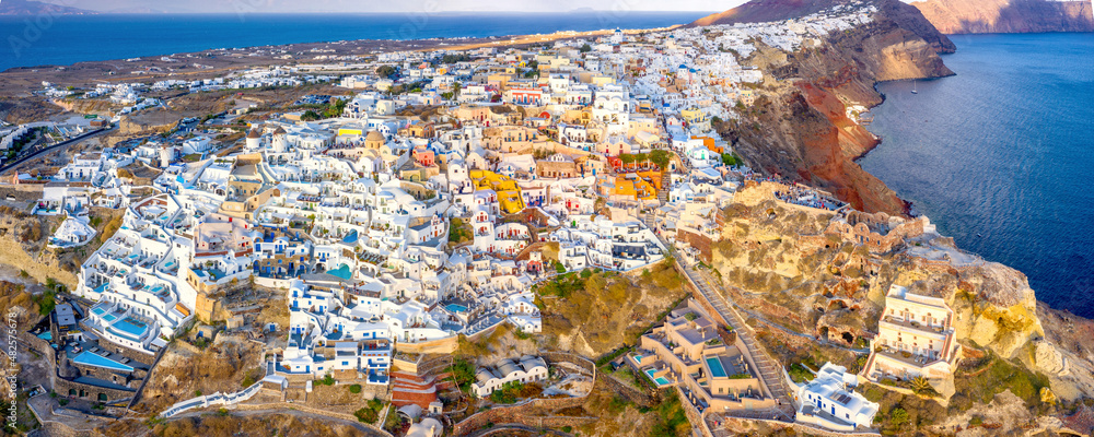 Picturesque Aerial drone view of famous Oia village with white houses during sunrise on Santorini island, Greece, Europe. Luxury travel. Summer holidays. Travel concept background.