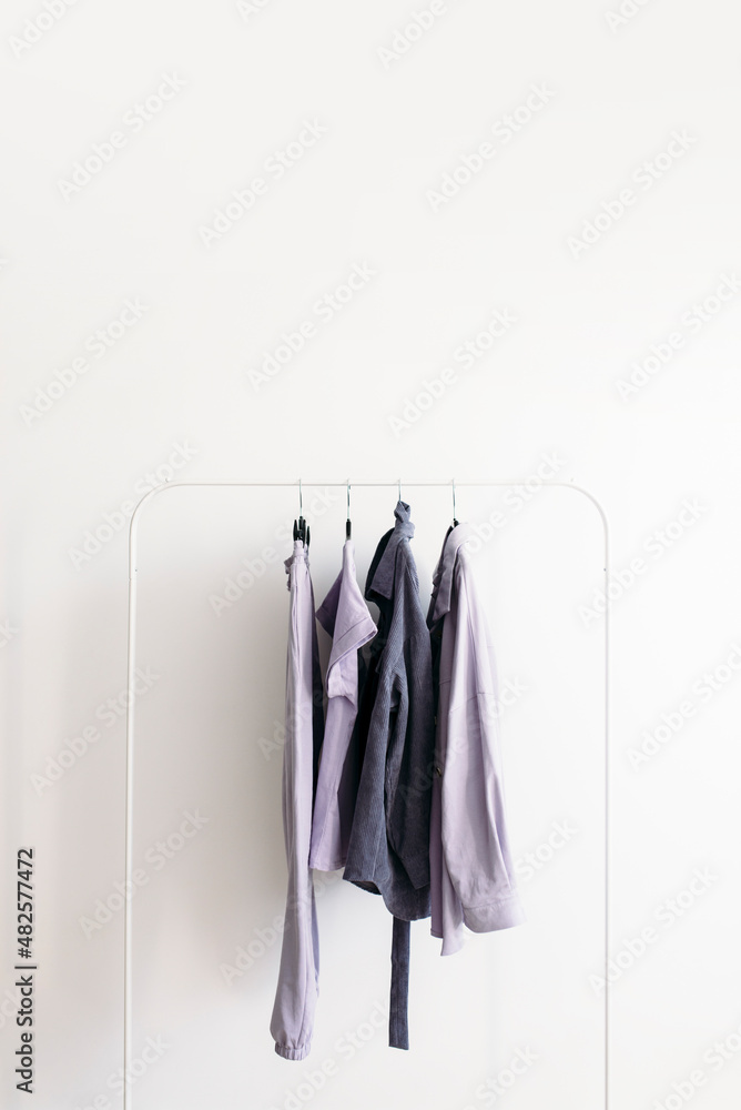 Rack with capsule clothes in gray and pastel lavender colors Minimalism concept