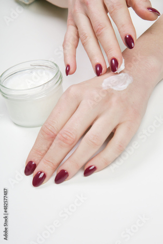Woman applying protective cream on hands. Cold season hands skin protection. An open jar of cream and woman s hands on table. Organic cosmetics for skin care. Beauty concept.