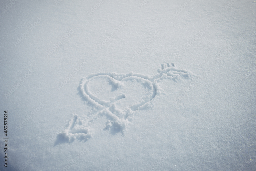 Heart with arrow, drawn in snow. Love symbol painted on white snowy background. Romantic relationship concept. Heart with arrow, drawn in snow. Love symbol painted on white snowy background. Romantic relationship concept.