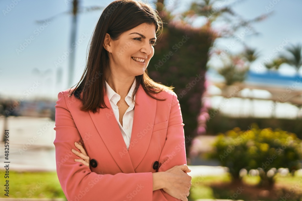 Beautiful hispanic business woman wearing elegant jacket smiling happy at the city with arms closed Beautiful hispanic business woman wearing elegant jacket smiling happy at the city with arms closed