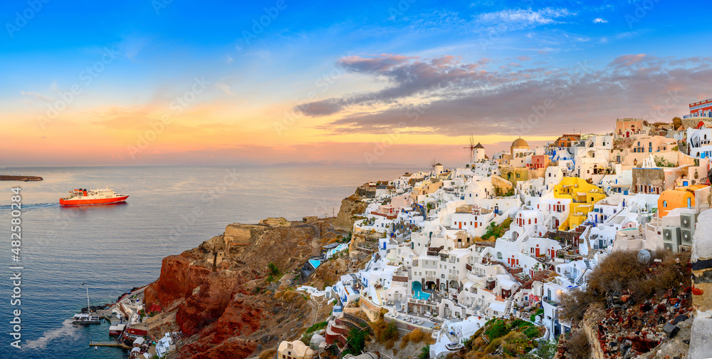 Fantastic Sunset view of traditional Greek village Oia on Santorini island, Greece, Europe. luxury travel. Passenger ferry sailing to the island. Summer holidays. Travel concept background.