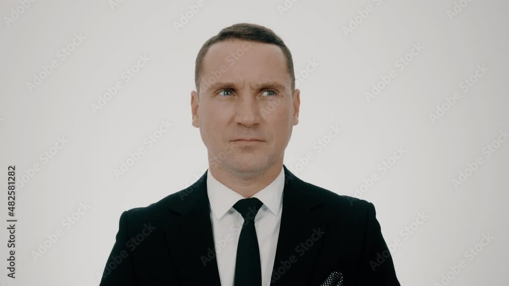 Young male businessman 30 years old, close-up in a black suit. He furrows his brows and gets angry. Young male businessman 30 years old, close-up in a black suit. He furrows his brows and gets angry.