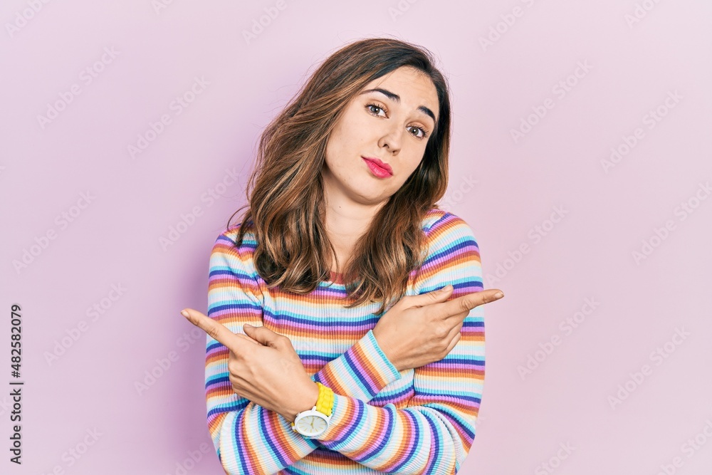 Young hispanic girl wearing casual clothes pointing to both sides with fingers, different direction disagree Young hispanic girl wearing casual clothes pointing to both sides with fingers, different direction disagree