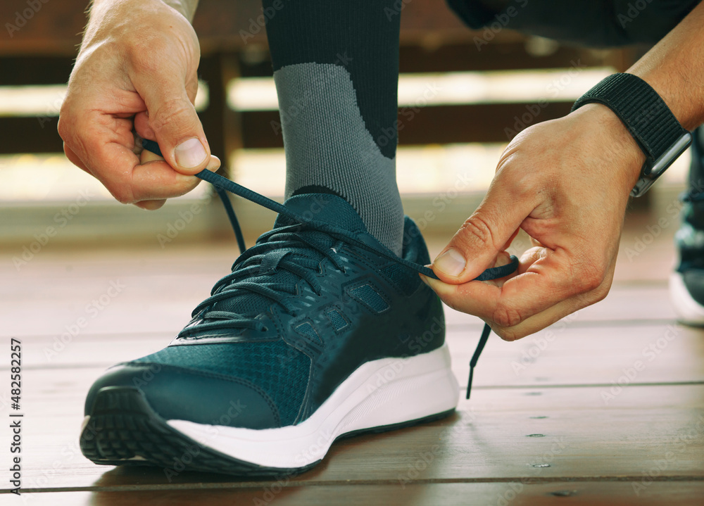 Fototapeta premium Guy preparing for running and laces up on the sneakers