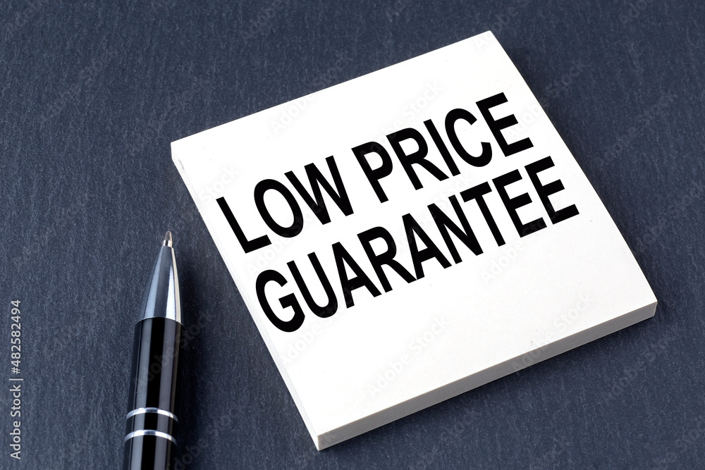LOW PRICE GUARANTEE text on the sticker with pen on the black background LOW PRICE GUARANTEE text on the sticker with pen on the black background