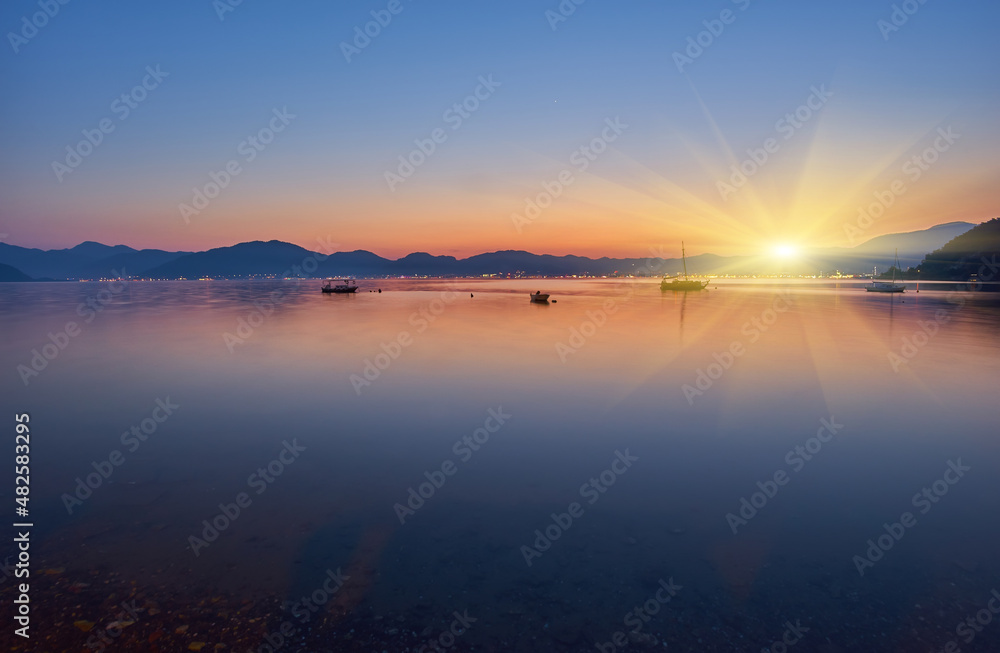 evening of mountain and small boat in the sea with yellow sun light in the sky background, sunset
