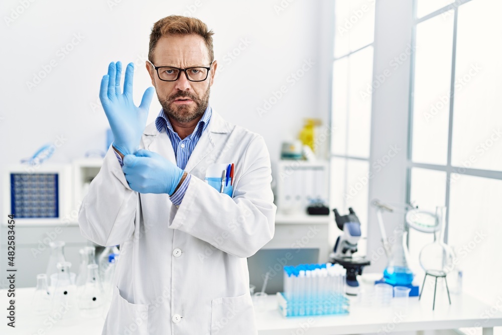 Middle age man working at scientist laboratory clueless and confused expression. doubt concept. Middle age man working at scientist laboratory clueless and confused expression. doubt concept.