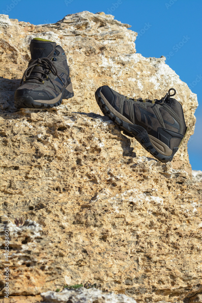 a pair of hiking boots, olive green on a natural background of sea and rocks a pair of hiking boots, olive green on a natural background of sea and rocks