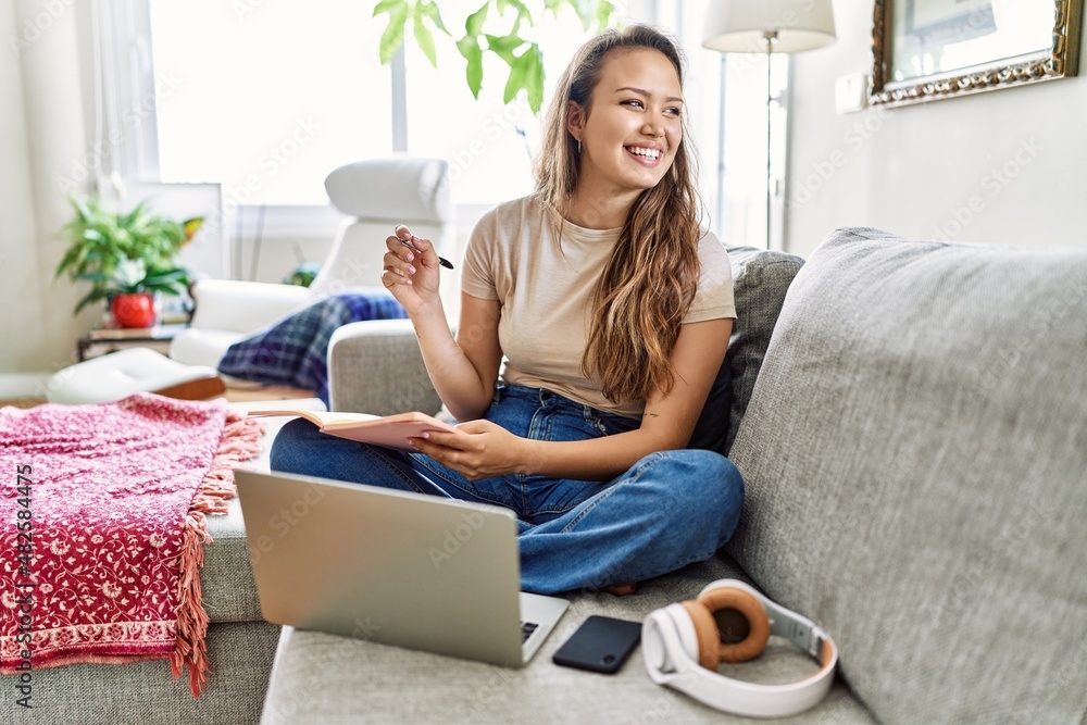 Young hispanic girl having online class sitting on the sofa at home. Young hispanic girl having online class sitting on the sofa at home.