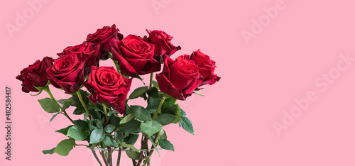 Bouquet of red roses in vase against pink background. Valentines day gift.