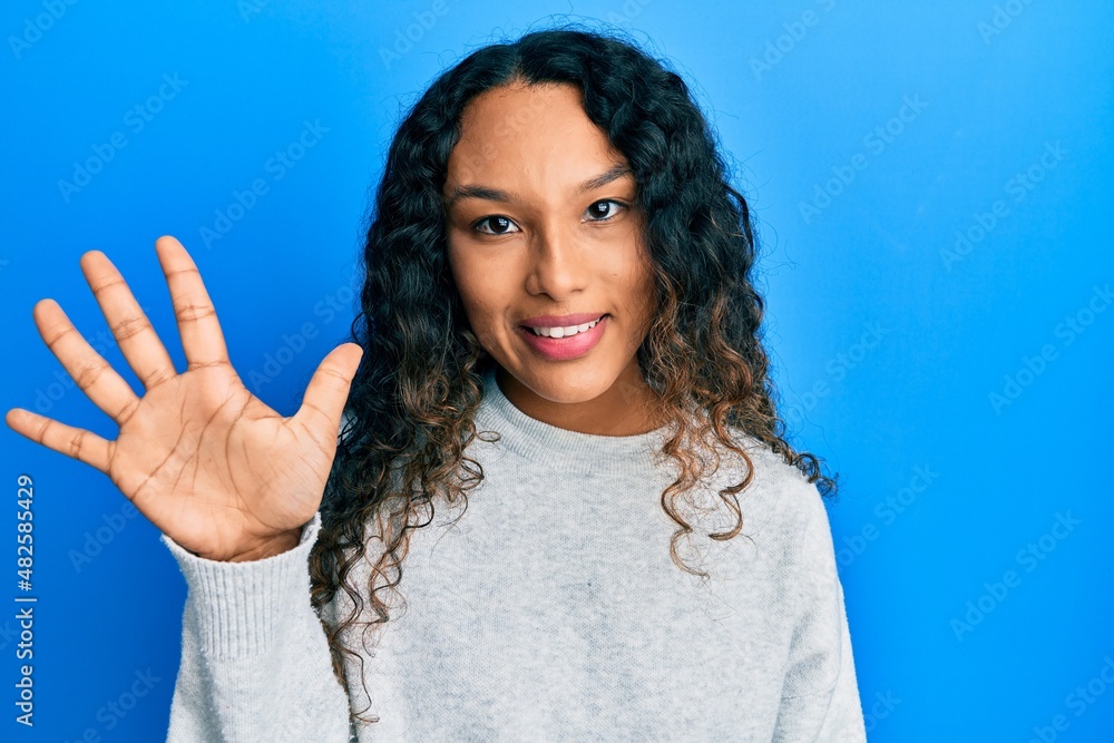 Young latin woman wearing casual clothes showing and pointing up with fingers number five while smiling confident and happy. Young latin woman wearing casual clothes showing and pointing up with fingers number five while smiling confident and happy.