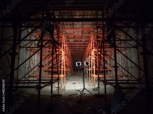 Interior of a bridge deck under construction supported by scaffolding, illuminated by spotlights