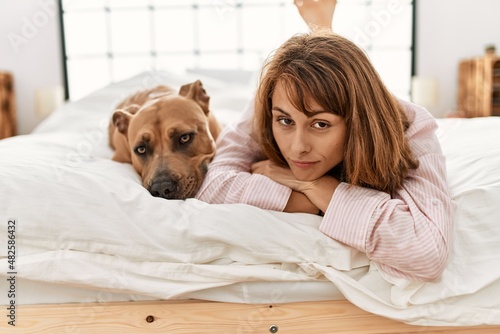 Young caucasian woman lying on bed with dog at bedroom