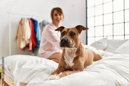 Young caucasian woman smiling confident sitting on bed with dog at bedroom