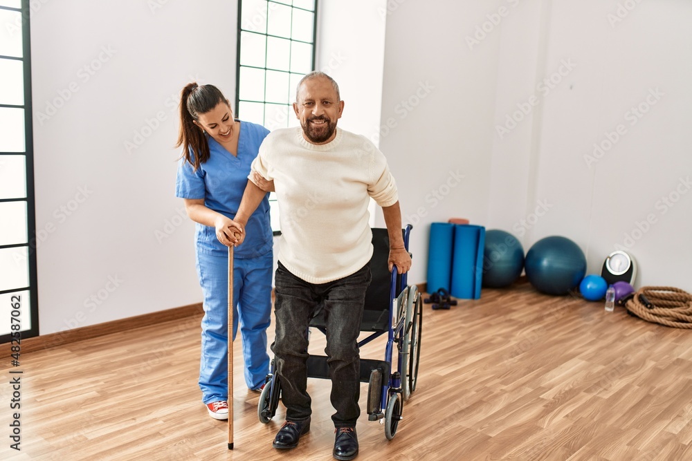 Senior man sitting on wheelchair being assited by geriatric nurse, handicapped mature man getting help to stand up Senior man sitting on wheelchair being assited by geriatric nurse, handicapped mature man getting help to stand up