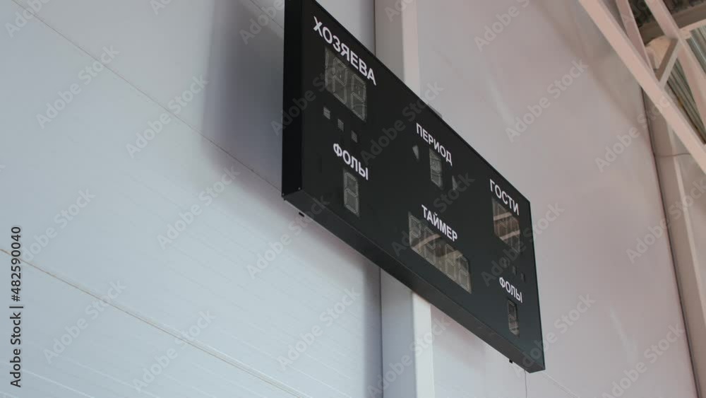 Contemporary black digital scoreboard for competitions hangs on white wall in large light hall of sports complex Contemporary black digital scoreboard for competitions hangs on white wall in large light hall of sports complex